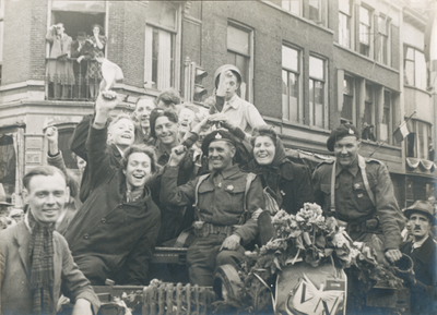 879259 Afbeelding van een voertuig, volgeladen met bevrijders en feestvierende mensen tijdens de intocht van de ...